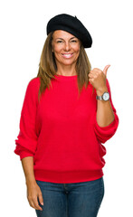 Middle age adult woman wearing fashion beret over isolated background doing happy thumbs up gesture with hand. Approving expression looking at the camera with showing success.