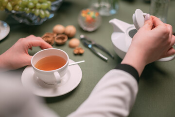 A festive sweet table is set, women are talking at the table. Women drink tea with dessert and fruits.