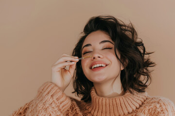 Obraz premium Happy Young Woman Applying Skincare with Dropper in Cozy Sweater on Neutral Background