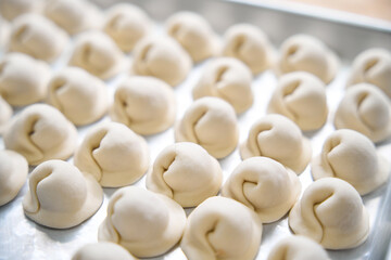 Handmade dumplings lie on a metal sheet