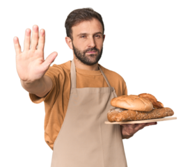 Hispanic male baker with bread tray standing with outstretched hand showing stop sign, preventing you.