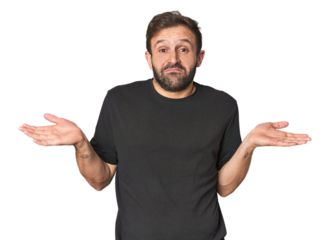 Studio portrait of young Hispanic male doubting and shrugging shoulders in questioning gesture.