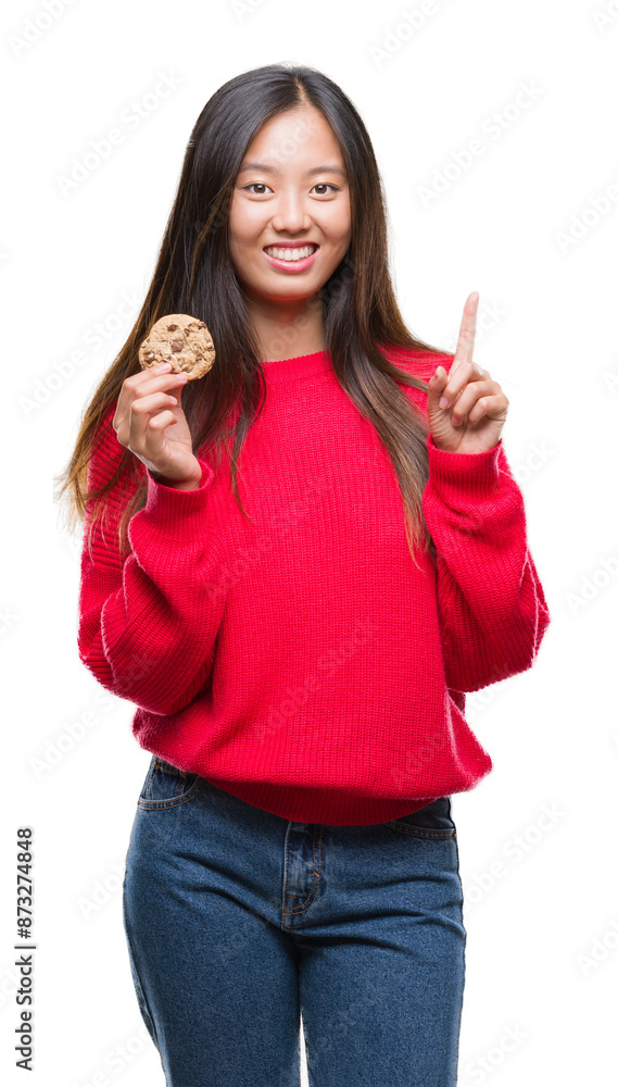 Sticker young asian woman eating chocolate chip cookie over isolated background surprised with an idea or qu