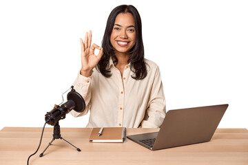 Woman records podcast with laptop cheerful and confident showing ok gesture.