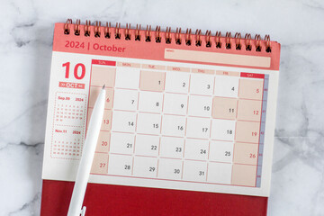 Desk calendar for October 2024 on marble background.