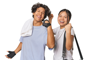 Young interracial athletic couple in studio raising fist after a victory, winner concept.