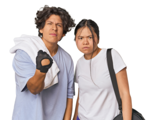 Young interracial athletic couple in studio showing fist to camera, aggressive facial expression.