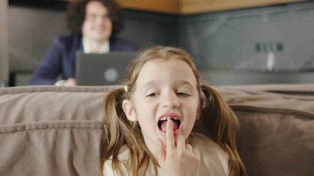 The child shakes the front baby tooth and smiles a toothless smile close-up. Changing teeth to molars in childhood