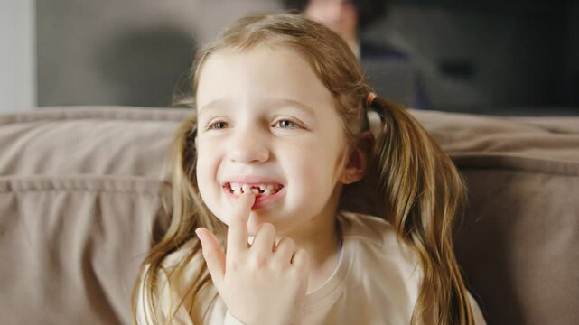 The child shakes the front baby tooth and smiles a toothless smile close-up. Changing teeth to molars in childhood
