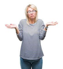 Young beautiful blonde woman wearing glasses over isolated background clueless and confused expression with arms and hands raised. Doubt concept.