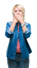 Young beautiful blonde woman wearing denim jacket over isolated background shocked covering mouth with hands for mistake. Secret concept.