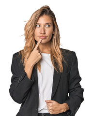 Young businesswoman in a suit looking sideways with doubtful and skeptical expression.