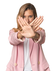 Young blonde in stylish pink suit doing a denial gesture