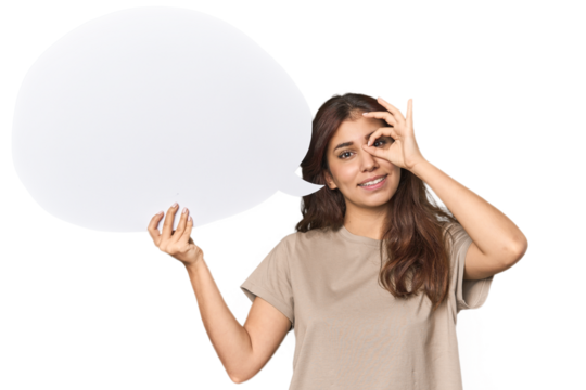 Middle Eastern woman holding comic bubble excited keeping ok gesture on eye.