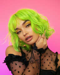 Transgender woman bright green hair, posing confidently against soft pink studio background