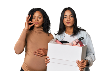 Latin women couple moving, one pregnant  with fingers on lips keeping a secret.