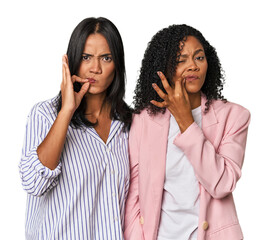 Young Latin businesswomen in studio with fingers on lips keeping a secret.