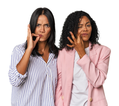 Young Latin businesswomen in studio with fingers on lips keeping a secret.