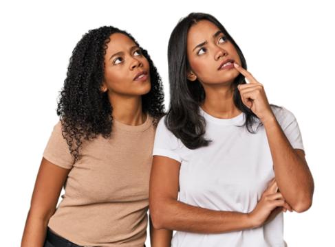 Young Latin friends in studio looking sideways with doubtful and skeptical expression.