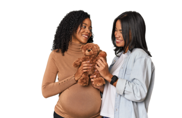Two Latin women, one pregnant, with teddy bear in studio
