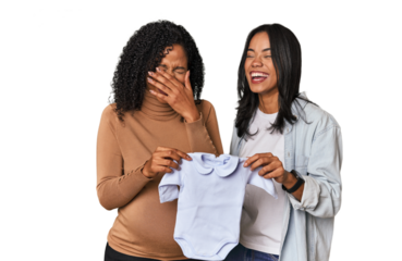 Two Latin women, one pregnant, with baby's bodysuit in studio