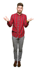 Young handsome man clueless and confused expression with arms and hands raised. Doubt concept.