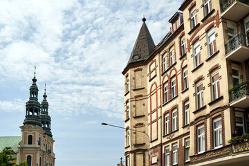 facade of a historic tenement house and bell towers of a baroque church in the city of Poznan