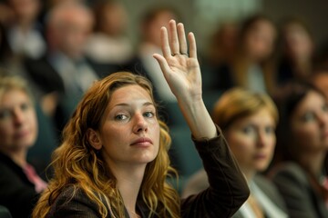 Fototapeta premium A businesswoman raises her hand with a confident expression amidst a blurred audience at a conference