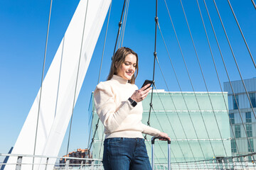 Female traveler using smartphone on a sunny bridge