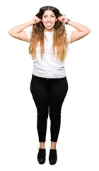 Fototapeta premium Young beautiful woman wearing casual white t-shirt Smiling pulling ears with fingers, funny gesture. Audition problem
