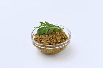 green olive and arugula tapenade in a bowl on a white background close-up