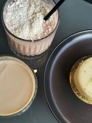 Top view of two ice-coffee with desert in cafe. Vertical photo