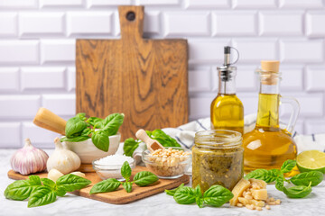 Pesto. Italian basil pesto sauce on a textured wooden background. Ingredient for pesto sauce: fresh basil, pine nuts, Parmesan cheese and olive oil. Space for text.Copy space.