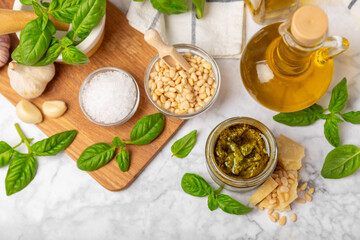 Pesto. Italian basil pesto sauce on a textured wooden background. Ingredient for pesto sauce: fresh basil, pine nuts, Parmesan cheese and olive oil. Space for text.Copy space.