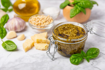 Pesto. Italian basil pesto sauce on a textured wooden background. Ingredient for pesto sauce: fresh basil, pine nuts, Parmesan cheese and olive oil. Space for text.Copy space.