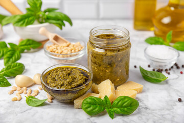 Pesto. Italian basil pesto sauce on a textured wooden background. Ingredient for pesto sauce: fresh basil, pine nuts, Parmesan cheese and olive oil. Space for text.Copy space.