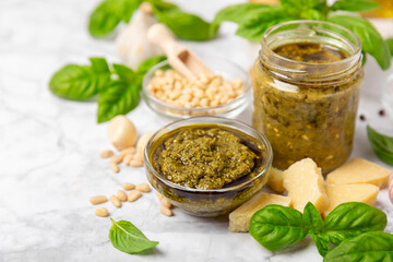 Pesto. Italian basil pesto sauce on a textured wooden background. Ingredient for pesto sauce: fresh basil, pine nuts, Parmesan cheese and olive oil. Space for text.Copy space.