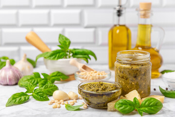 Pesto. Italian basil pesto sauce on a textured wooden background. Ingredient for pesto sauce: fresh basil, pine nuts, Parmesan cheese and olive oil. Space for text.Copy space.