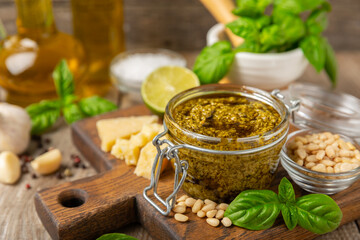 Pesto. Italian basil pesto sauce on a textured wooden background. Ingredient for pesto sauce: fresh basil, pine nuts, Parmesan cheese and olive oil. Space for text.Copy space.