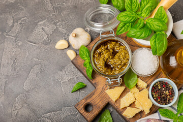 Pesto. Italian basil pesto sauce on a textured wooden background. Ingredient for pesto sauce: fresh basil, pine nuts, Parmesan cheese and olive oil. Space for text.Copy space.