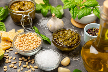 Pesto. Italian basil pesto sauce on a textured wooden background. Ingredient for pesto sauce: fresh basil, pine nuts, Parmesan cheese and olive oil. Space for text.Copy space.