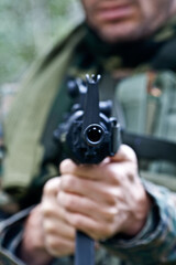 A soldier wearing camouflage cloth is directing an air gun to shoot.