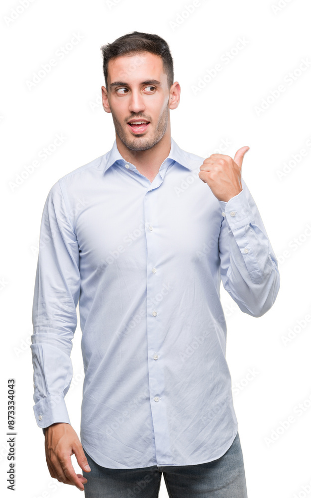 Wall mural Handsome young businessman smiling with happy face looking and pointing to the side with thumb up.