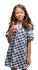 Brunette hispanic girl wearing black and white dress happy with big smile doing ok sign, thumb up with fingers, excellent sign