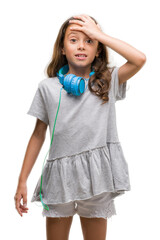 Brunette hispanic girl wearing headphones stressed with hand on head, shocked with shame and surprise face, angry and frustrated. Fear and upset for mistake.