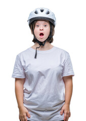 Young adult cyclist woman with down syndrome wearing safety helmet over isolated background afraid and shocked with surprise expression, fear and excited face.