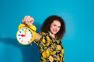 Photo of adorable cute girl wear trendy print clothes hold alarm clock isolated on blue color...