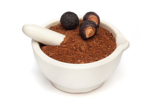 Close-up of Organic Soapnut or Reetha (Sapindus mukorossi) powder with its Fruits, in white ceramic mortar and pestle, isolated on a white background.