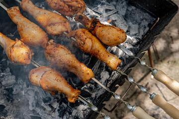 Chicken shanks on skewers on grill, grilling.