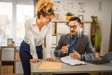 Two colleagues have consultation at office about work use laptop